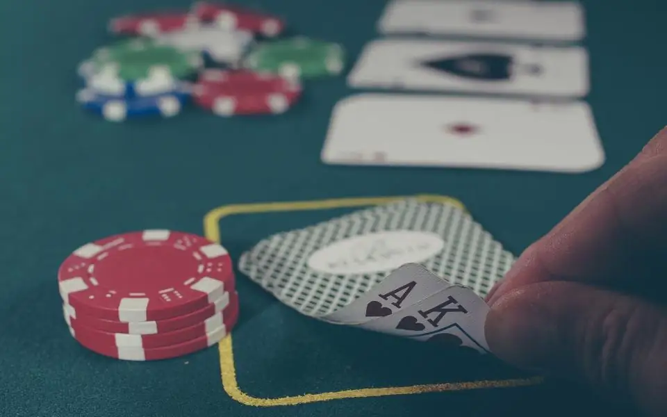 Player revealing an ace beside red poker chips on a green JLBETPH-style casino table